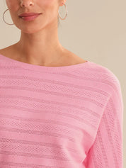 Close-up of a person wearing a pink sweater with a neutral background