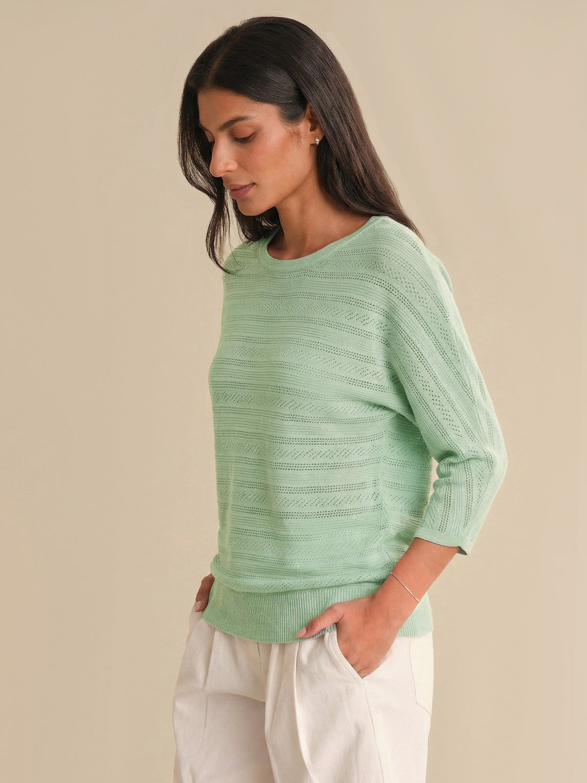 Woman wearing a light green sweater against a beige background