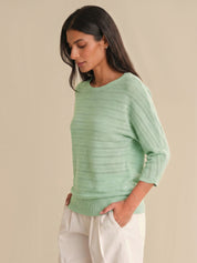 Woman wearing a light green sweater against a beige background