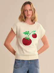 Woman wearing a cream sweater with red tomato design on a beige background
