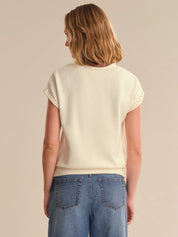 Woman wearing a cream sweater and blue jeans on a beige background