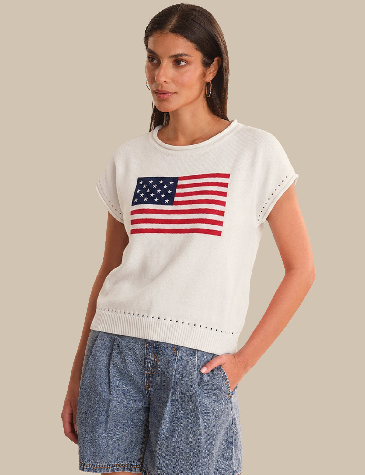 Woman wearing a white sweater with an American flag design on a beige background