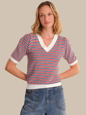 Woman wearing a red, white, and blue striped shirt with a beige background