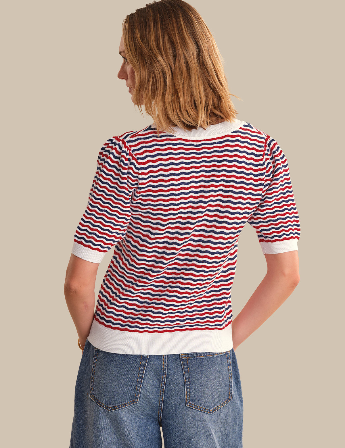 Woman wearing a red, white, and blue striped shirt with a beige background