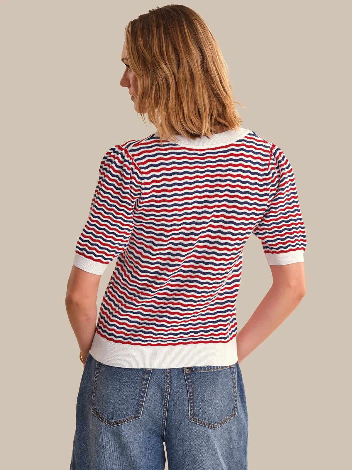Woman wearing a red, white, and blue striped shirt with a beige background