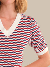 Person wearing a red, white, and blue striped shirt with a neutral background