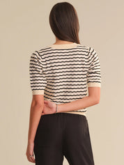 Woman wearing a black and white striped shirt with a beige background