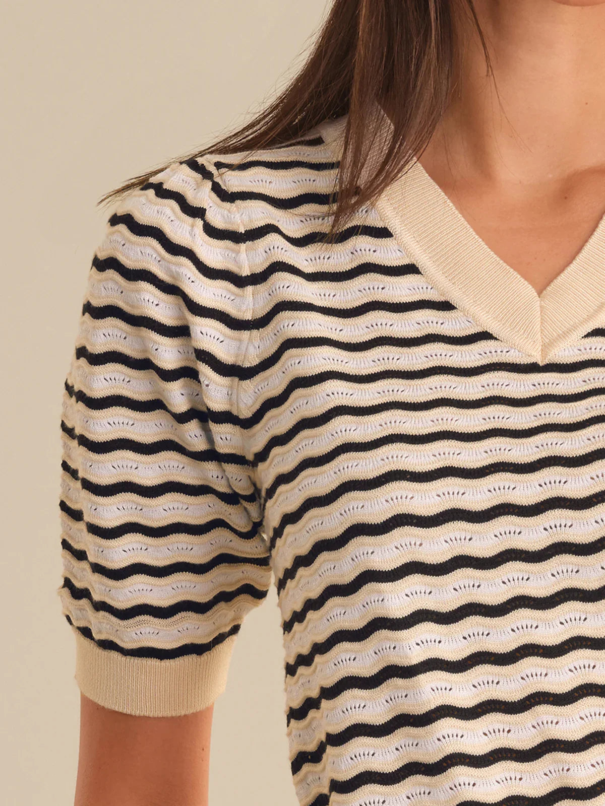 Close-up of a person wearing a striped shirt with wavy pattern on a beige background