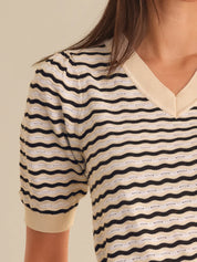 Close-up of a person wearing a striped shirt with wavy pattern on a beige background