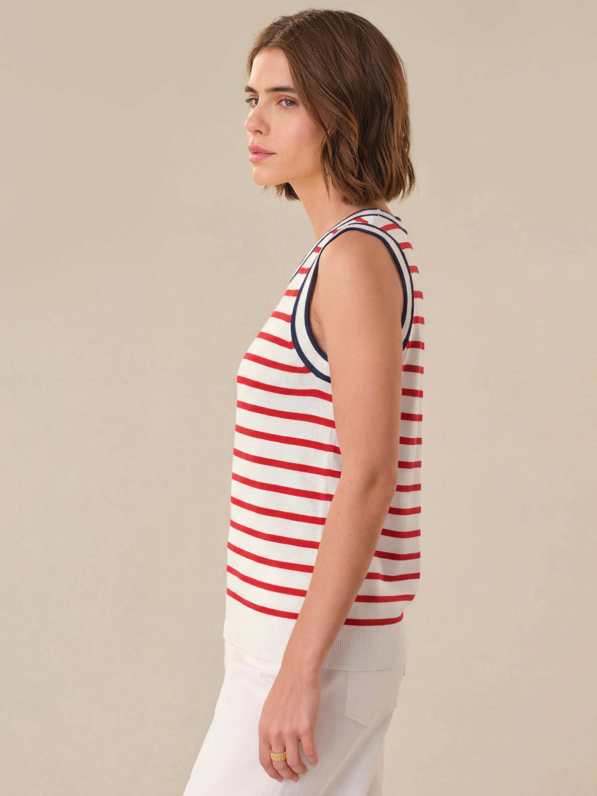 Woman wearing a red and white striped sleeveless top against a beige background