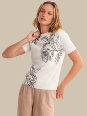 Woman wearing a white t-shirt with black floral patterns on a beige background