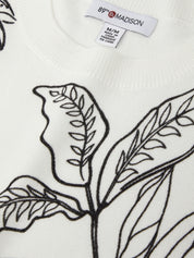 White sweater with black leaf pattern and '89 Madison' label.