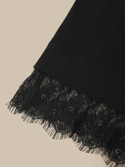Close-up of a black ribbed knit fabric with a matching black lace ruffle trim, shown against a light beige background.