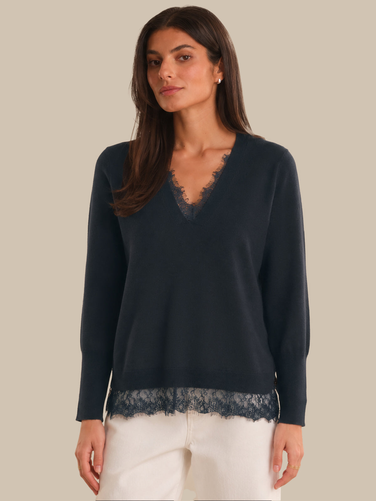 Woman wearing a navy blue sweater with lace trim on a beige background