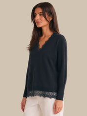 Woman wearing a navy blue sweater with lace trim on a beige background