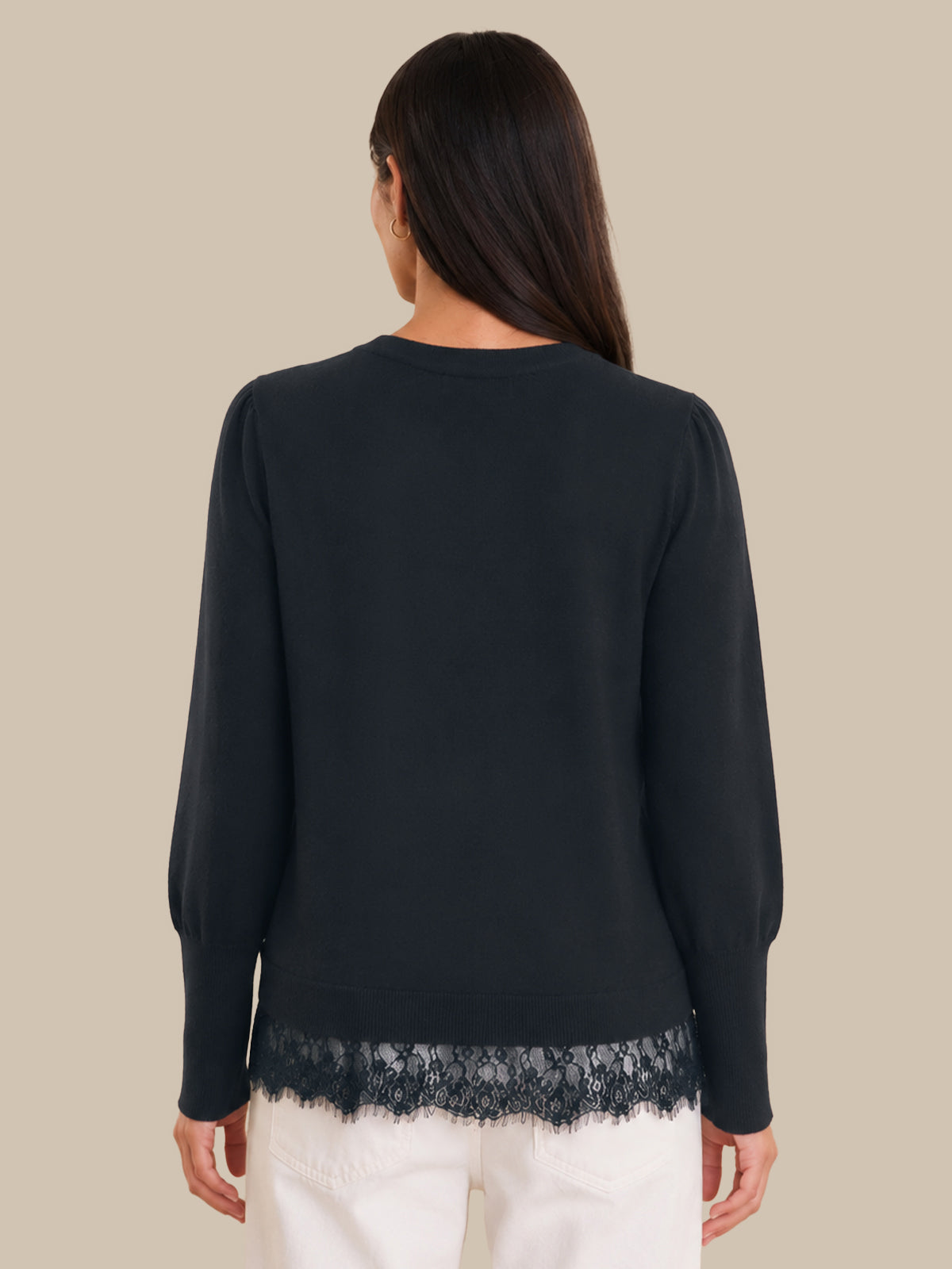 Woman wearing a black sweater with lace trim on a beige background