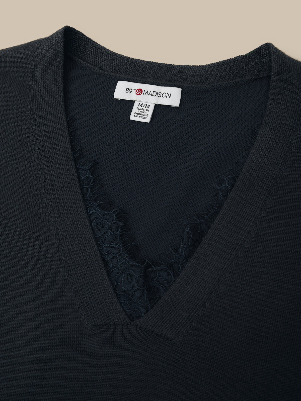 Black garment with a visible brand label on a beige background