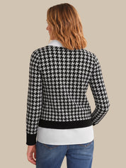 Person wearing a black and white houndstooth patterned sweater on a beige background