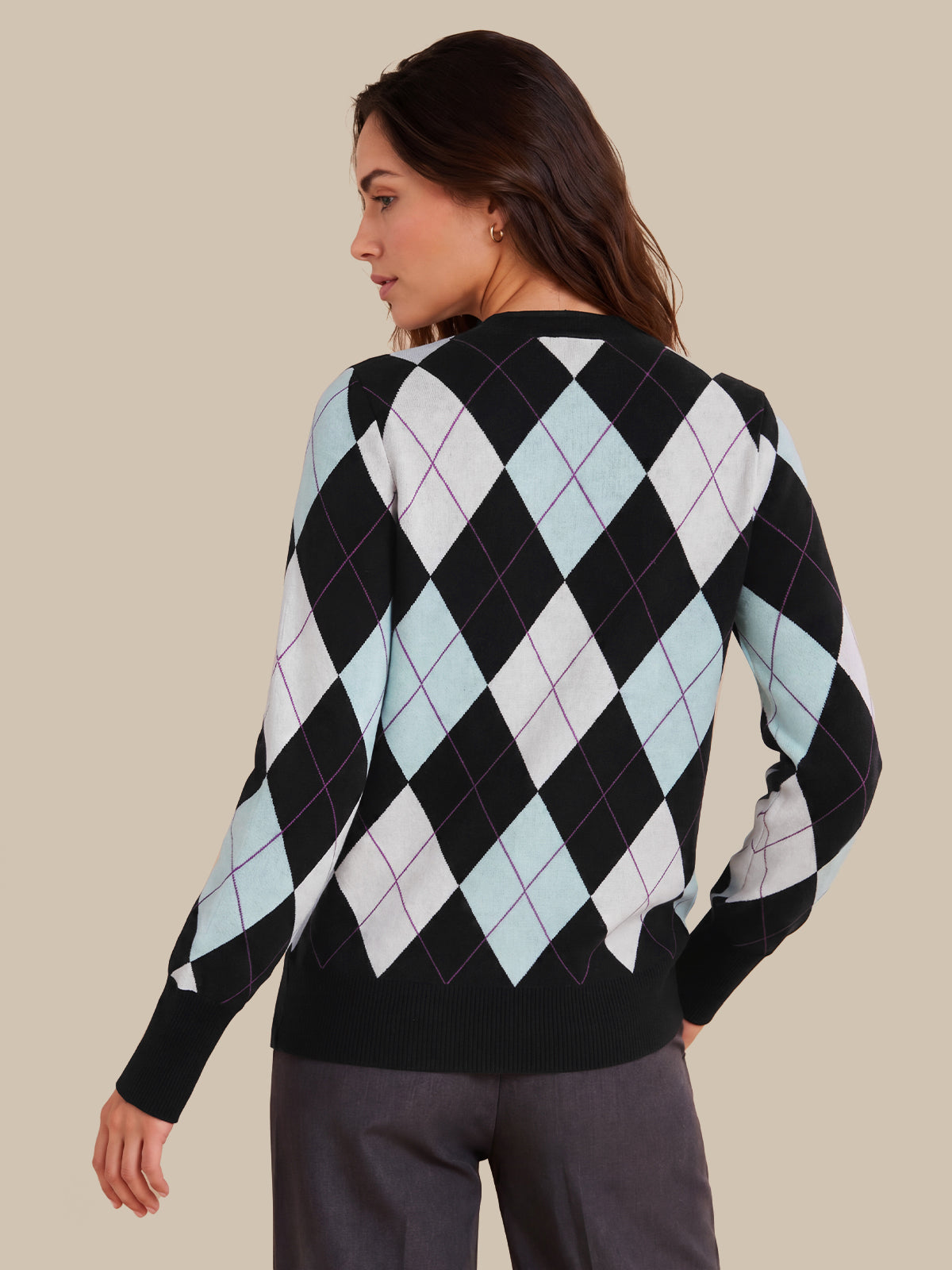 A woman shown from the back wearing a black sweater with a light blue, white, and black argyle pattern, paired with dark gray trousers, against a solid beige background.
