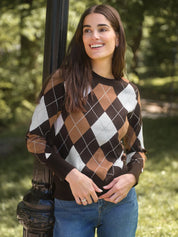 A woman wearing a brown, tan, and white argyle sweater leans against a dark metal pole in a sunny park setting.