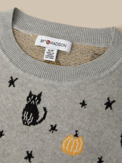 Close-up of a gray knit sweater with a black cat, yellow pumpkin, and black star pattern, featuring a visible 89th & Madison brand label at the collar.