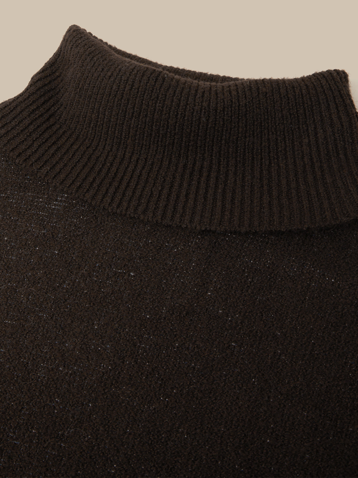 Close-up of a dark brown ribbed knit turtleneck sweater, showing the texture of the collar and fine knit details against a light beige background.