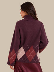 A woman shown from the back wearing a burgundy turtleneck sweater with an argyle diamond pattern in burgundy, dusty pink, and white on the lower back and sleeves, paired with a burgundy satin skirt against a solid beige background.