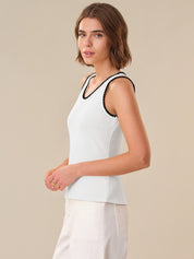 Woman wearing a white sleeveless top with black trim on a beige background
