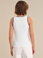 Woman wearing a white sleeveless top with black trim on a beige background