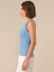 Woman wearing a light blue sleeveless top with a beige background