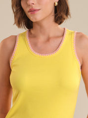 Yellow tank top with pink trim worn by a person, on a neutral background
