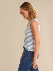 Woman wearing a striped tank top and blue jeans against a beige background