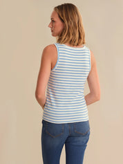Woman wearing a blue and white striped tank top and blue jeans on a beige background