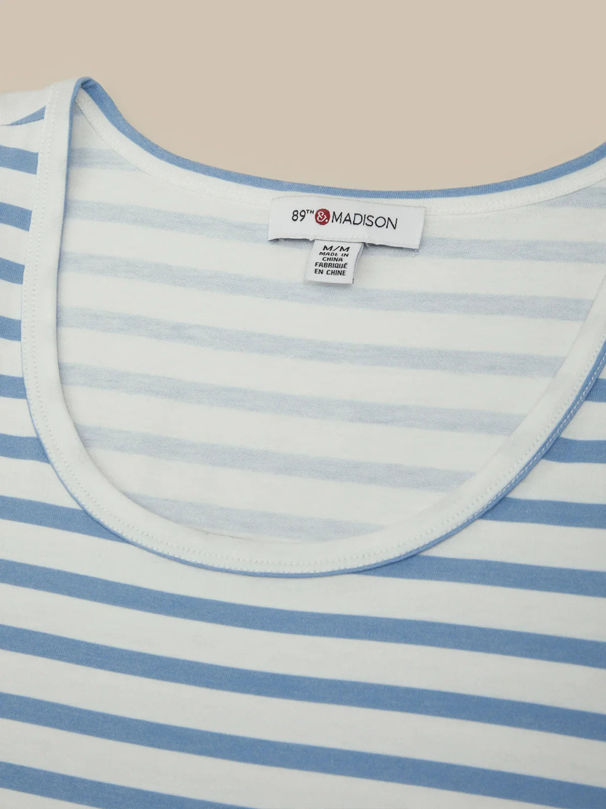 Close-up of a blue and white striped shirt with a brand label on a beige background