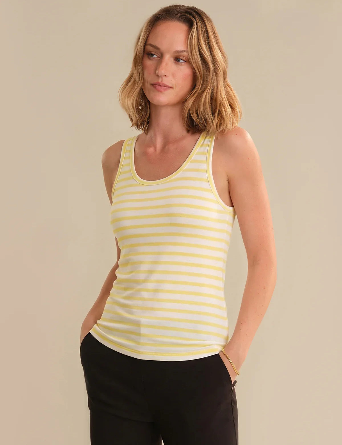 Woman wearing a yellow striped tank top against a beige background