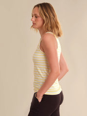 Woman wearing a yellow striped tank top against a beige background