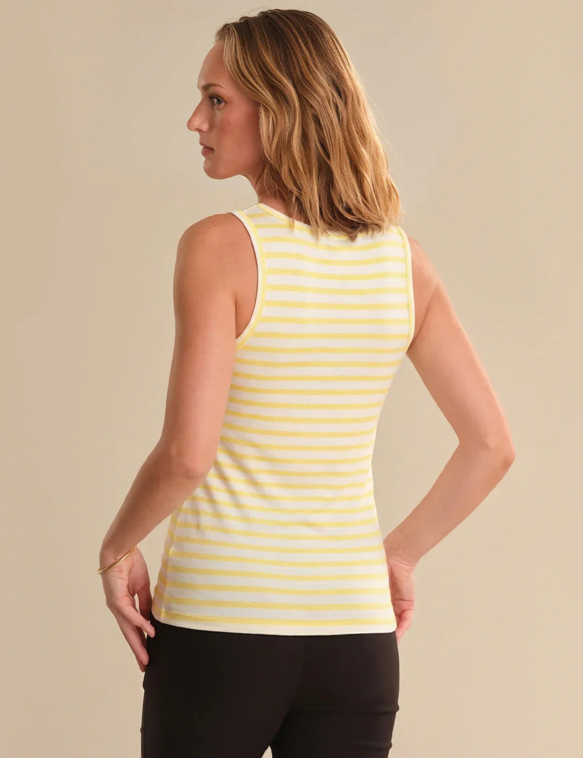 Woman wearing a yellow striped tank top against a beige background