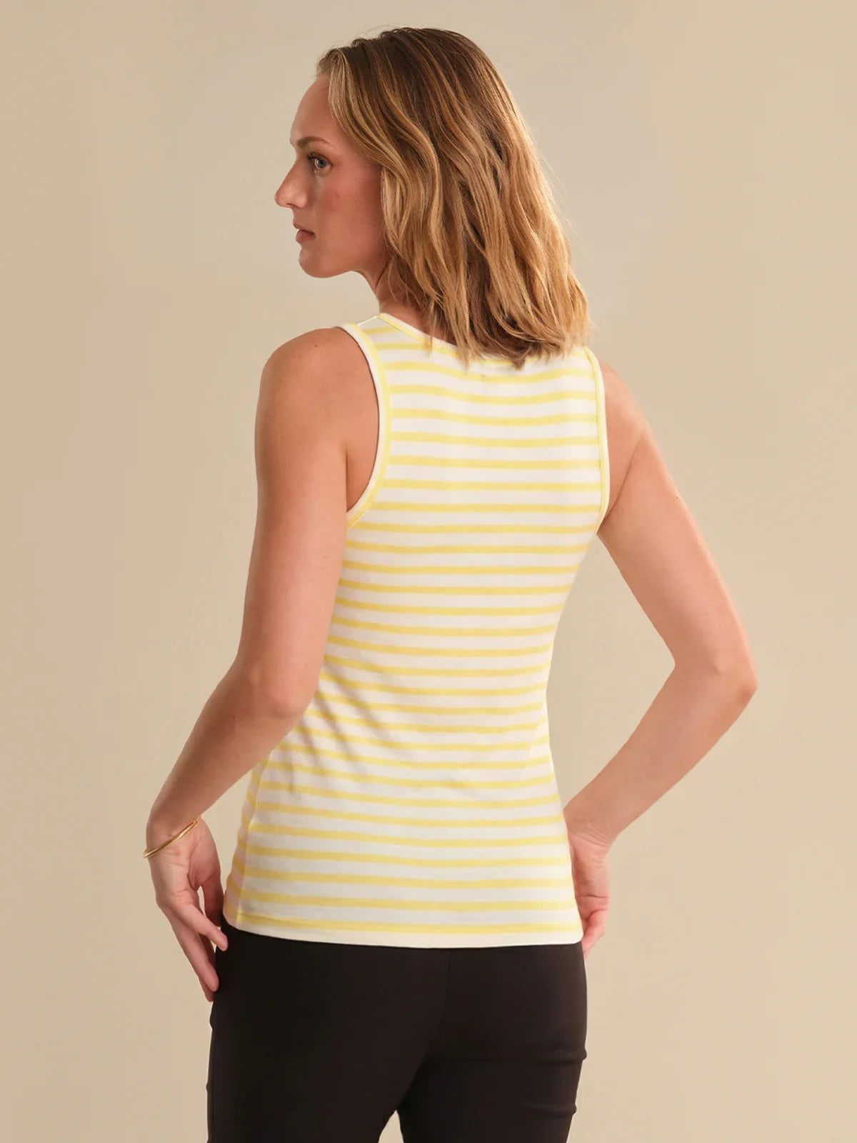 Woman wearing a yellow striped tank top against a beige background