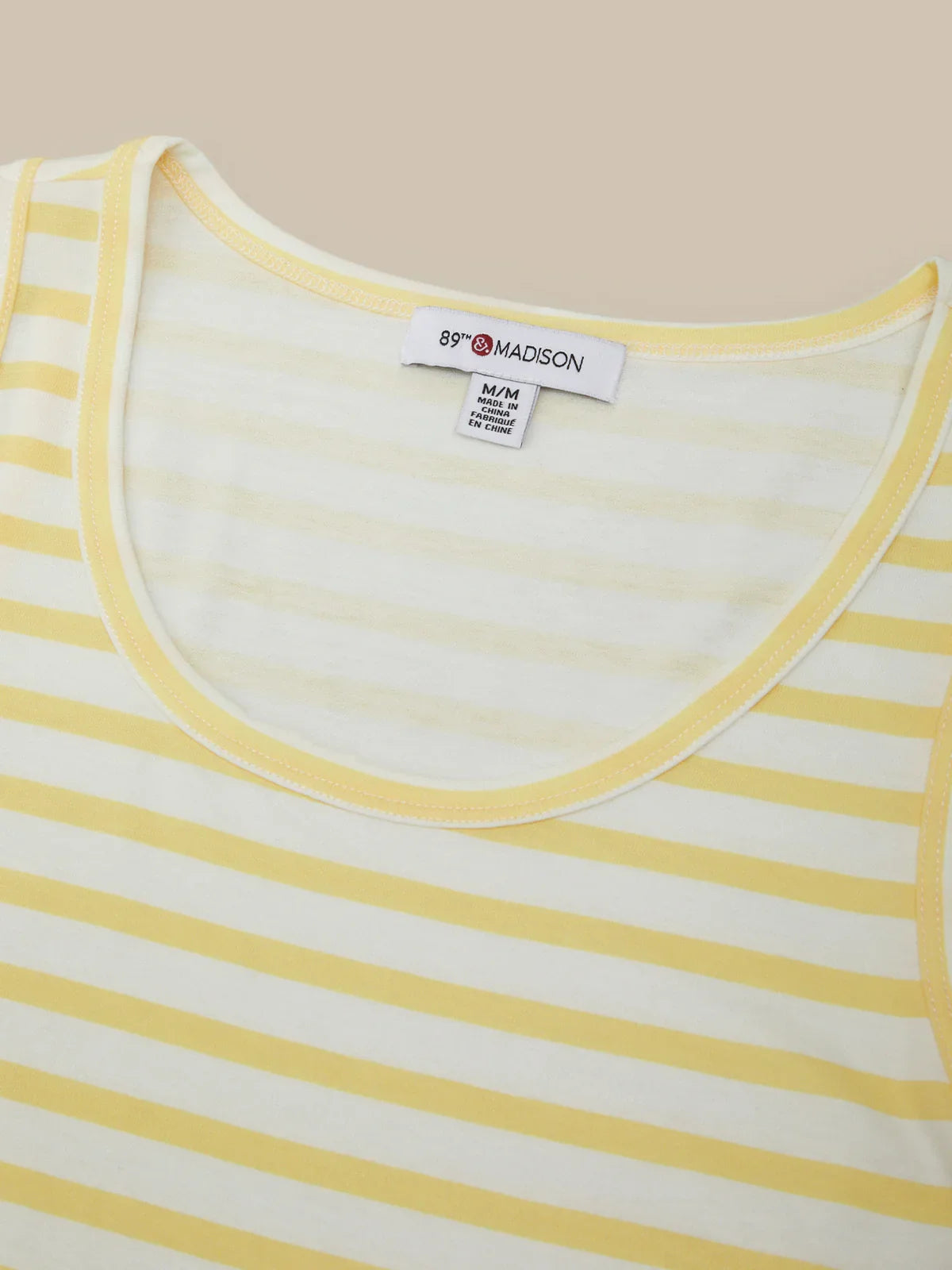 Close-up of a yellow and white striped shirt with a brand label on a beige background