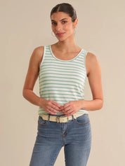 Woman wearing a green and white striped tank top and blue jeans on a beige background