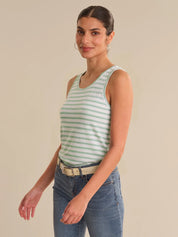 Woman wearing a green and white striped tank top and blue jeans on a beige background