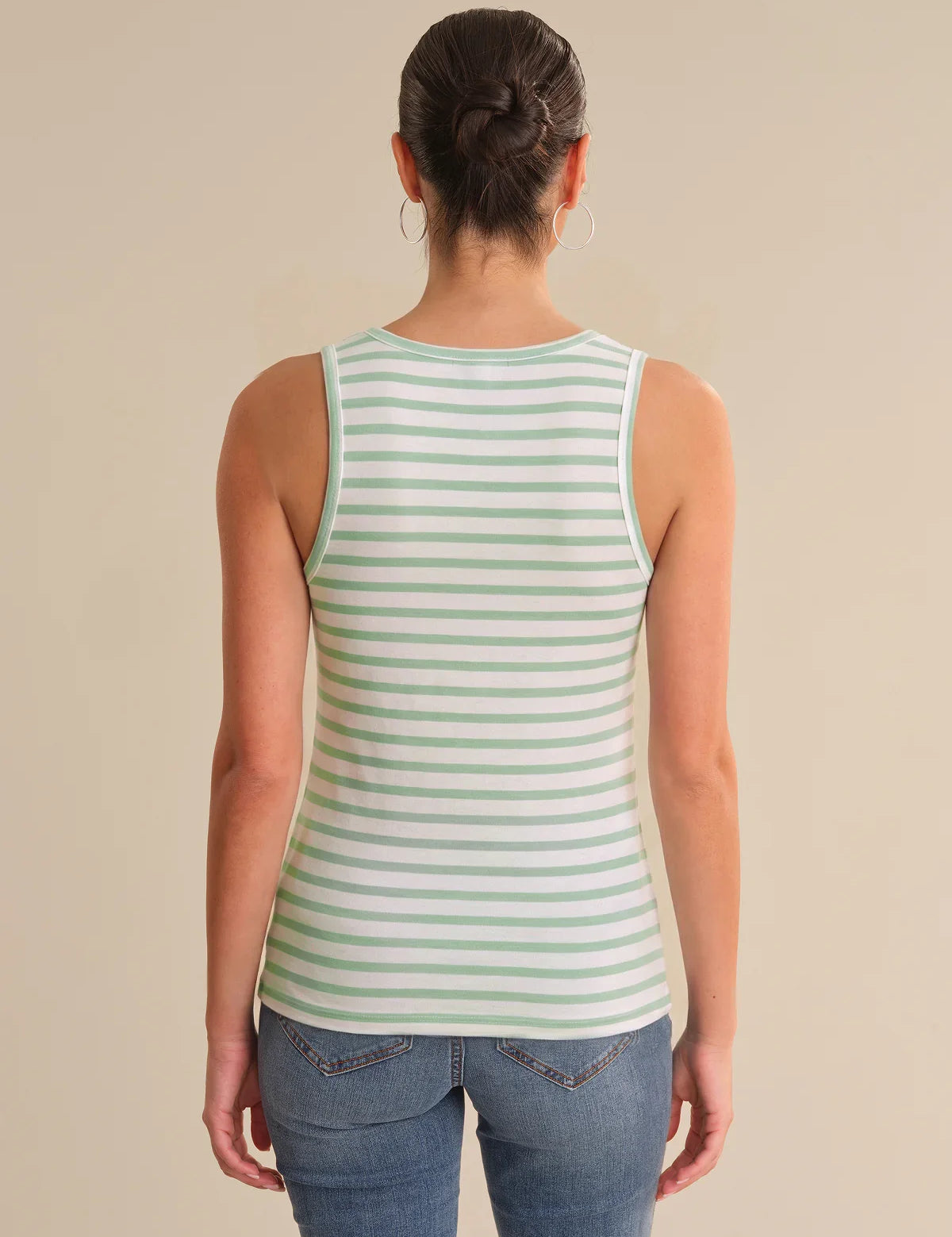 Person wearing a green and white striped tank top on a beige background