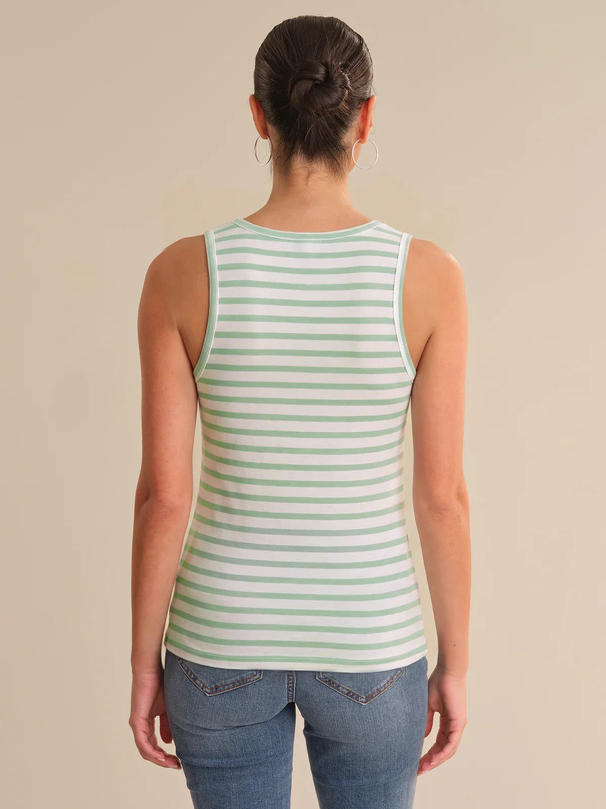 Person wearing a green and white striped tank top on a beige background