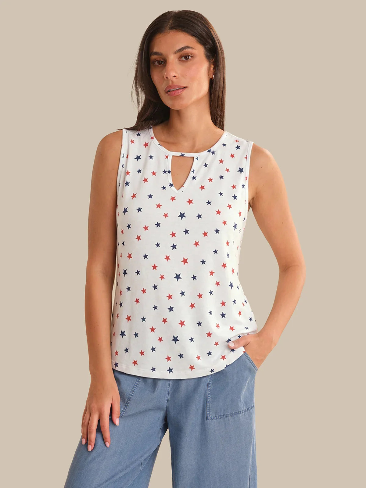 Woman wearing a sleeveless top with star pattern and blue jeans on a beige background