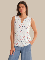 Woman wearing a sleeveless top with star pattern and blue jeans on a beige background