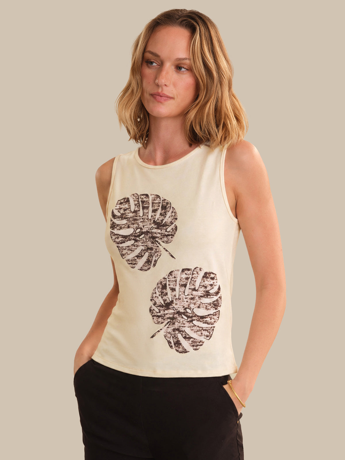Woman wearing a sleeveless top with leaf patterns on a beige background