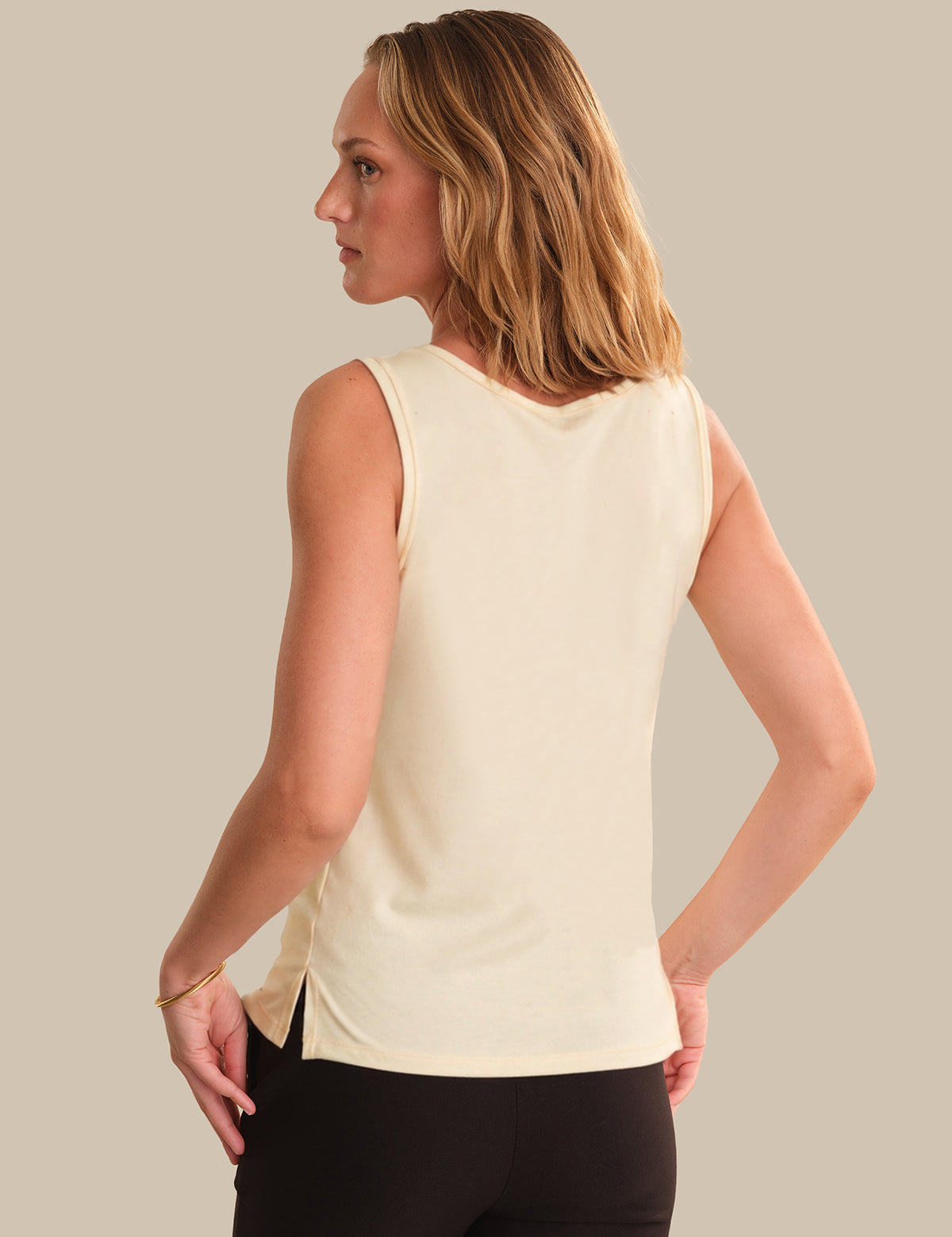 Woman wearing a light-colored sleeveless top against a neutral background