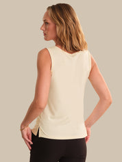 Woman wearing a light-colored sleeveless top against a neutral background