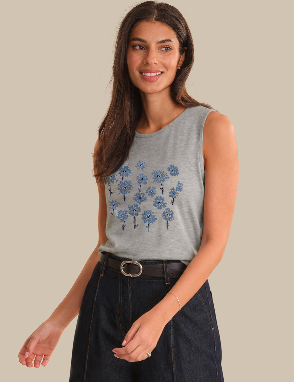 Woman wearing a gray sleeveless top with blue floral patterns on a beige background