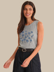 Woman wearing a gray sleeveless top with blue floral patterns on a beige background